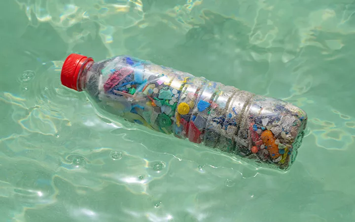 Mikroplastik in einer Plastikflasche, die im Wasser schwimmt