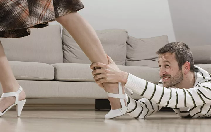 Ein Mann hält sich am Bein einer Frau fest, die weggehen möchte.